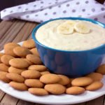 Banana Pudding Cheesecake Dip in a blue bowl with vanilla wafers around it