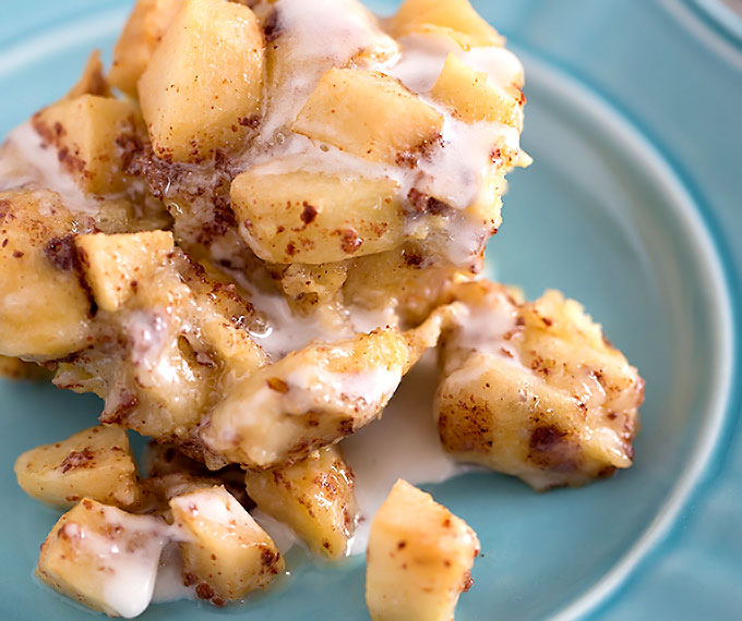 one serving of Crock Pot Apple Cinnamon Roll Casserole with icing on a blue plate