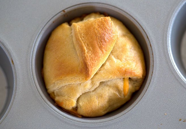 cooked stuffed crescent roll in a muffin tin
