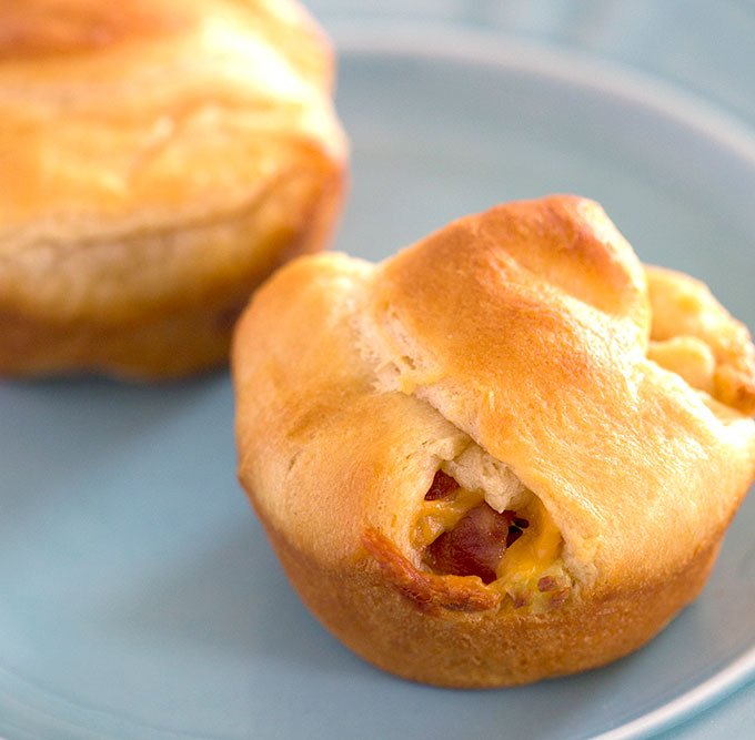 two cooked bacon egg and cheese crescents on a blue plate