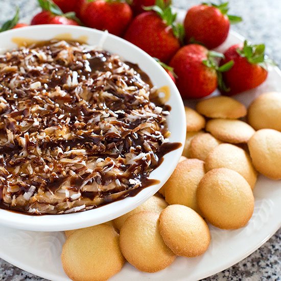 Samoas Dip in a serving bowl with fruit and cookies