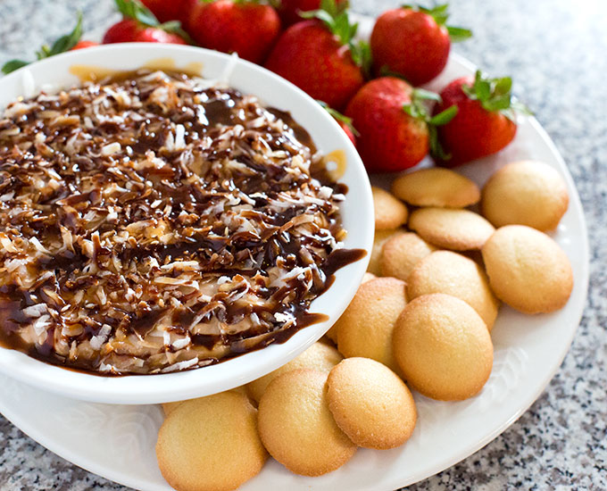Samoas Dip in a serving bowl with strawberries and vanilla wafers