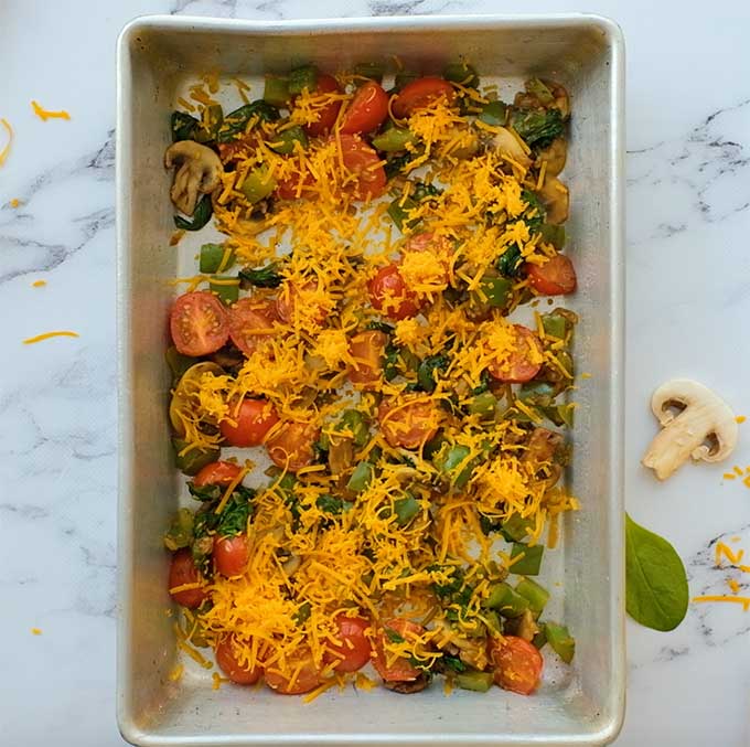 baking dish with sautéed veggies and shredded cheese