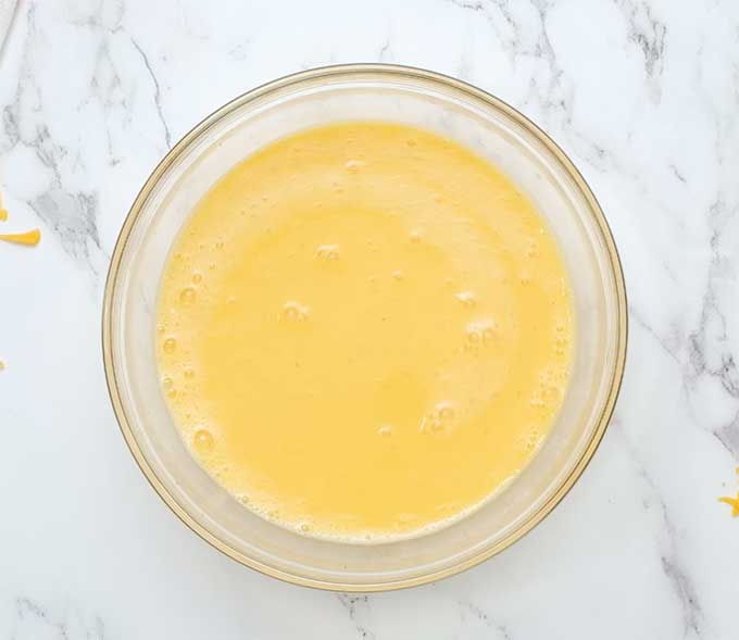 mixing bowl full of eggs mixed with milk, salt, and pepper