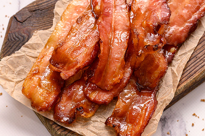 Pile of brown sugar baked bacon on a cutting board