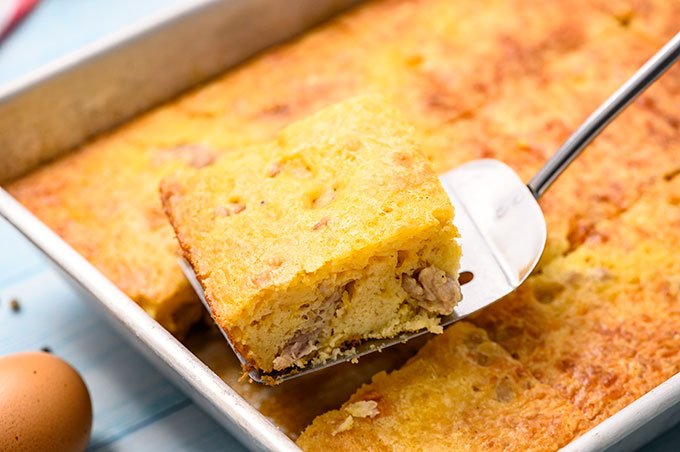 Slice of sausage breakfast casserole with bisquick being lifted out of a baking dish with a spatula.