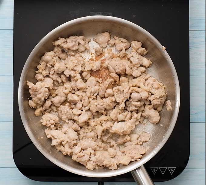 Breakfast sausage being browned in a skillet.