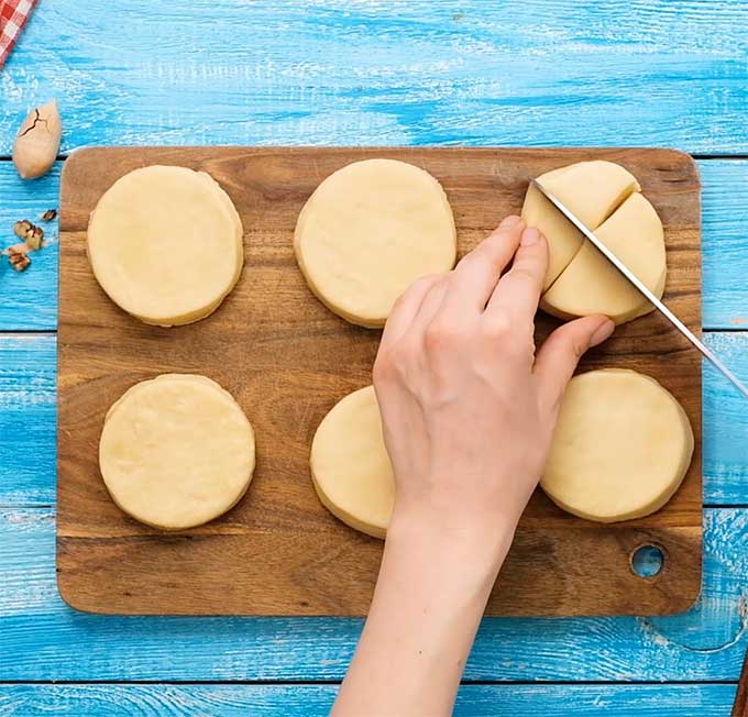 unbaked biscuit  dough on a cutting board being cut into quarters