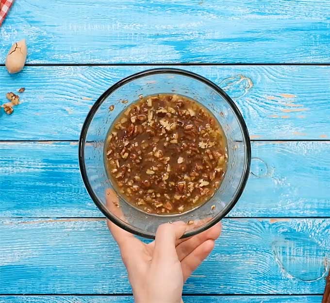 small glass bowl full of melted butter, brown sugar, and chopped pecans