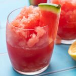 Glass full of watermelon slushy with a wedge of watermelon on the rim