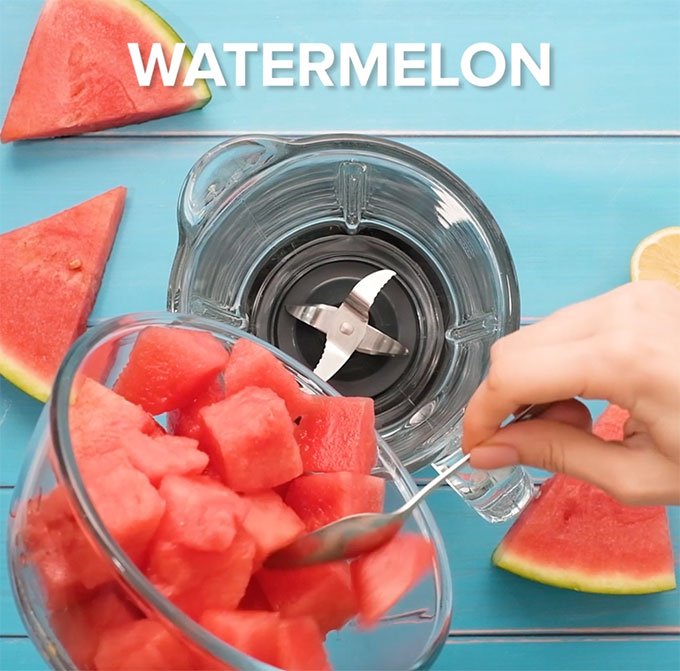 pouring chunks of watermelon into a blender