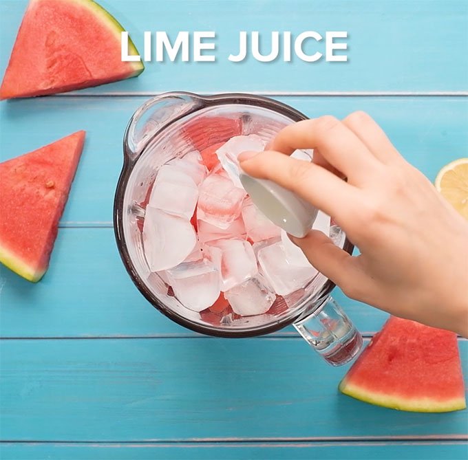 adding lime juice to a blender full of watermelon cubes and ice