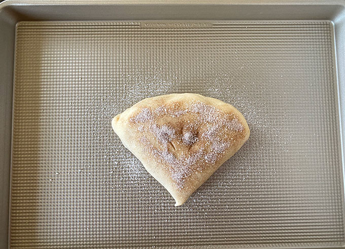 Folded pie crust with filling inside topped with cinnamon sugar