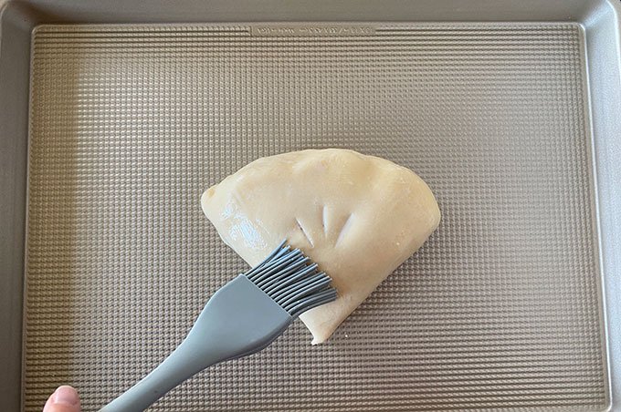 pie crust being brushed with milk