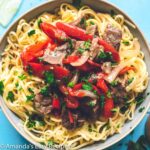 large bowl of pepper steak over cooked noodles