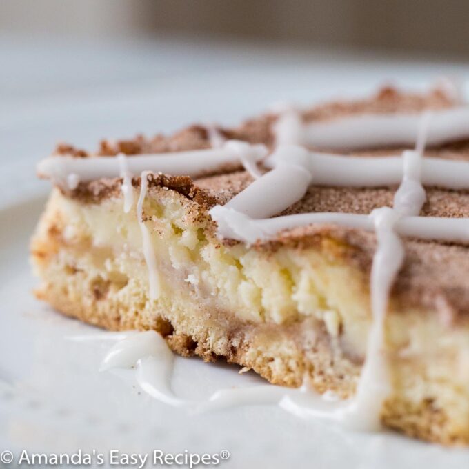 Slice of cinnamon roll cheesecake on a white plate.