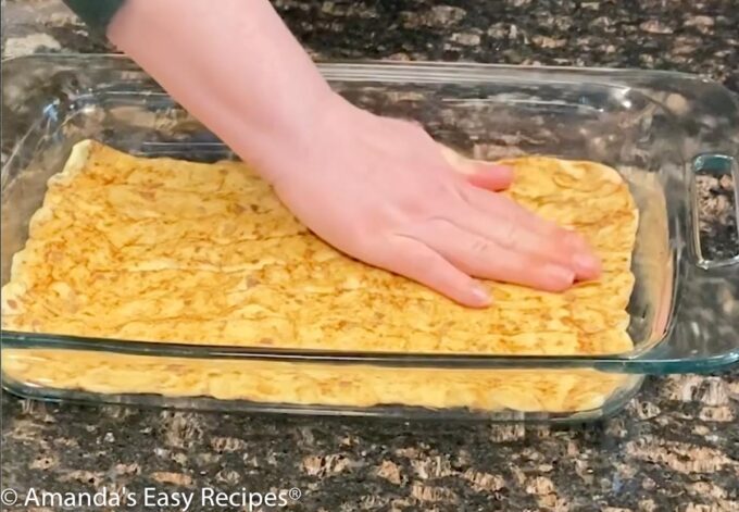 Forming the cinnamon roll crust in a baking dish.