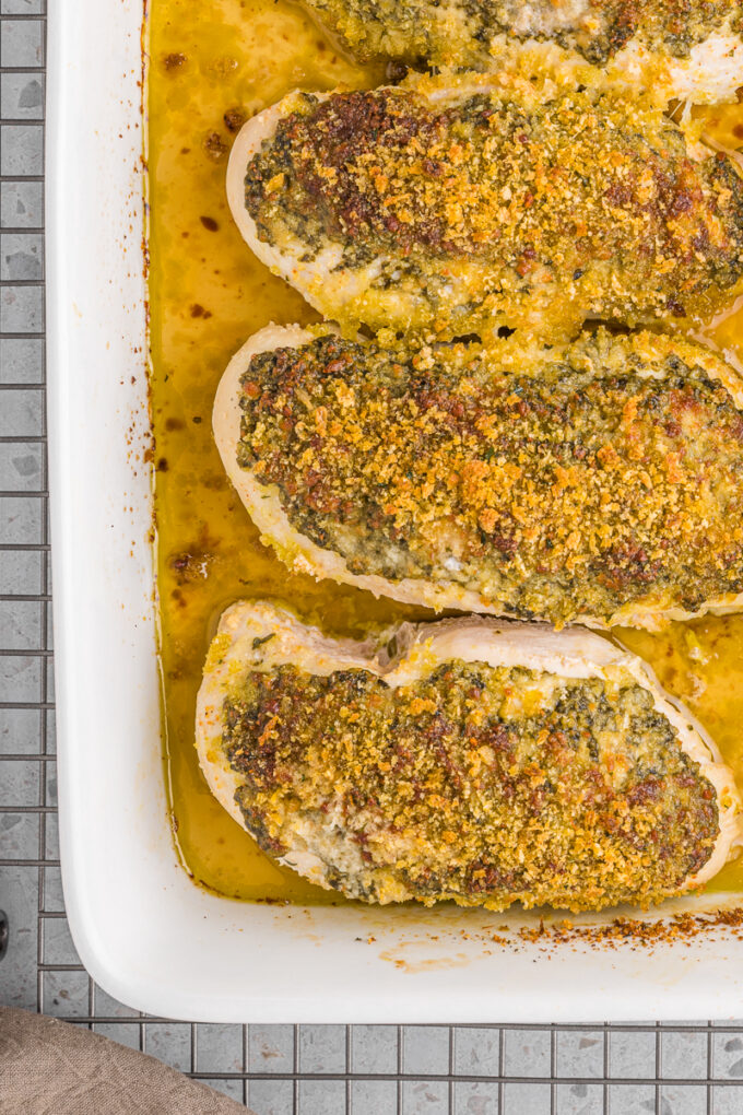 Baked pesto parmesan chicken breasts in a baking dish.