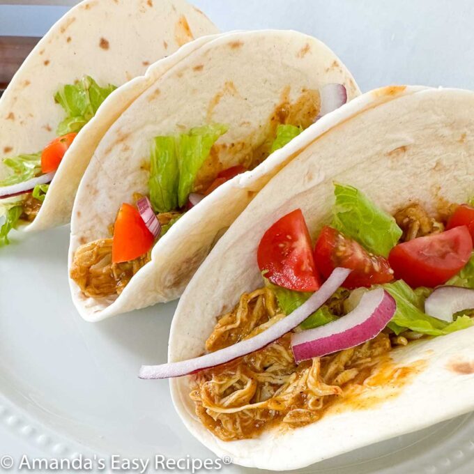 Three chicken soft tacos on a white plate.