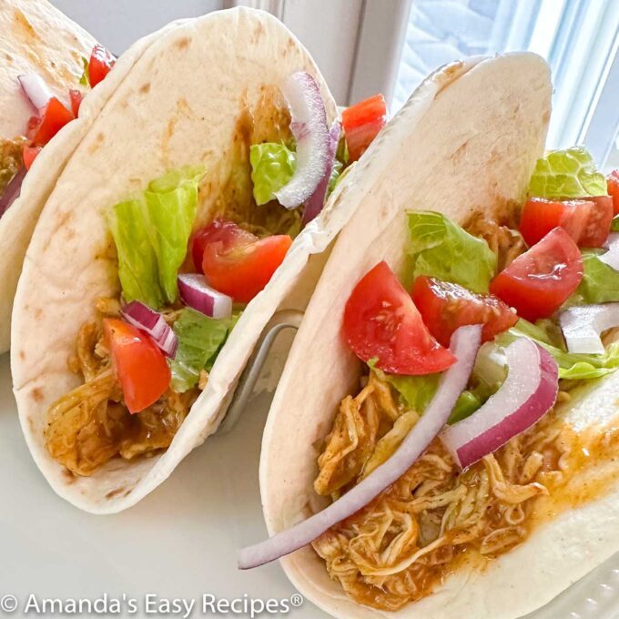 Chicken soft tacos on a white plate.