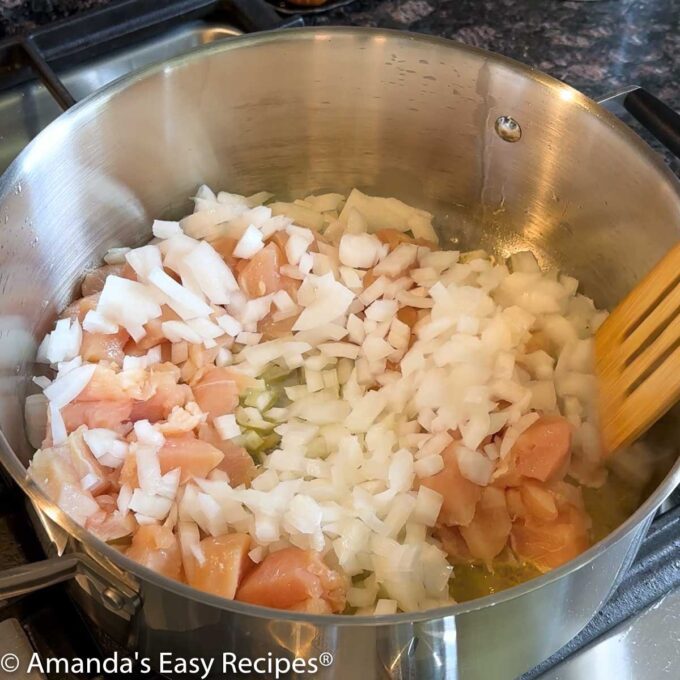 Large soup pot full of chopped chicken breast and onion.