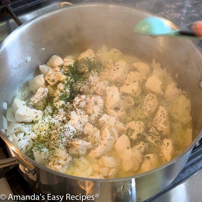 Adding seasoning to the chicken and onion in the soup pot.