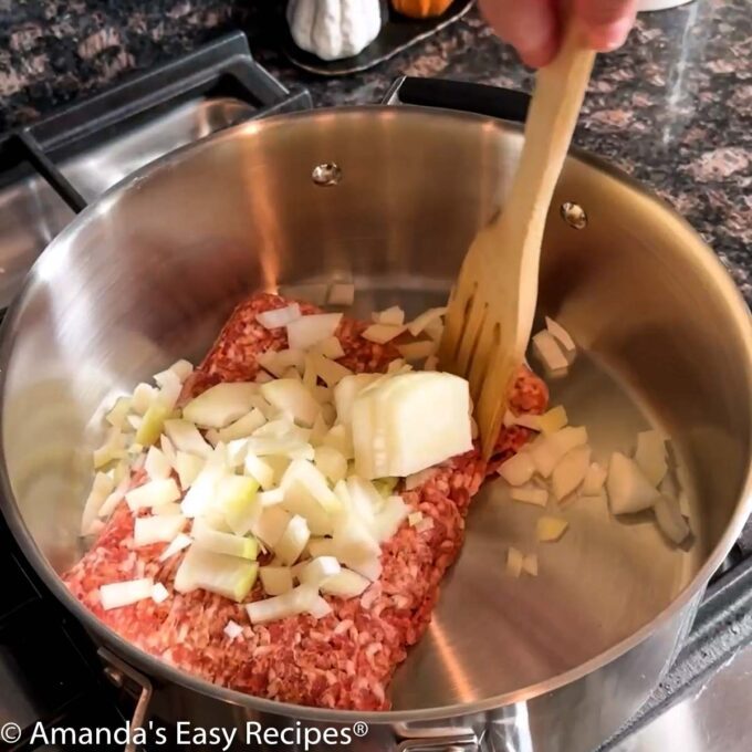 Cooking Italian sausage and chopped onion in a large soup pot.