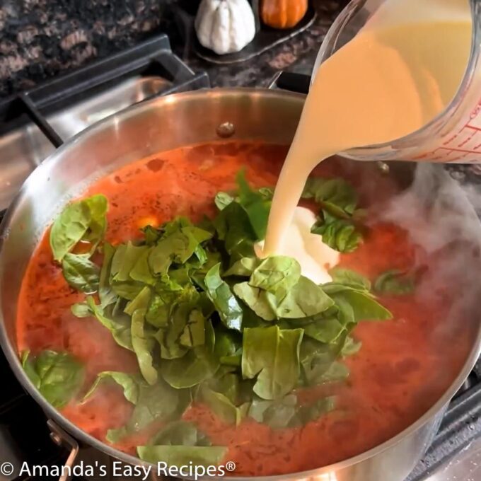 Adding frozen cheese tortellini, chopped spinach, and heavy cream to the pot.