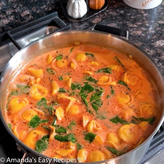 Simmering pot full of tortellini sausage soup.