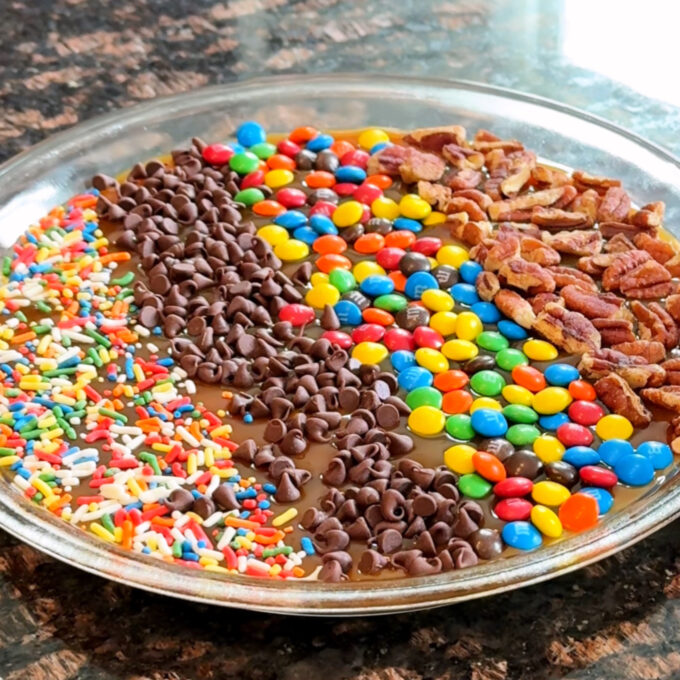 Caramel apple cheesecake dip with assorted toppings.