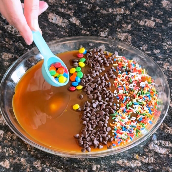 Sprinkling toppings over the caramel.