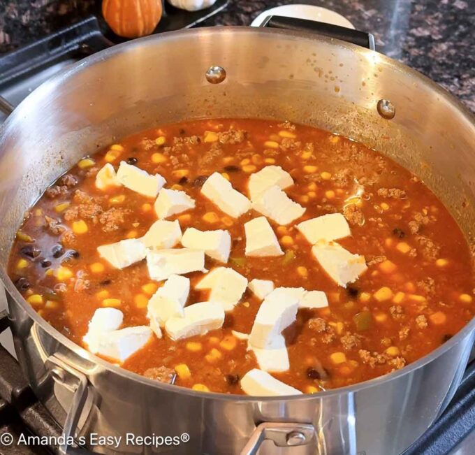 Adding cubed cream cheese to the pot.