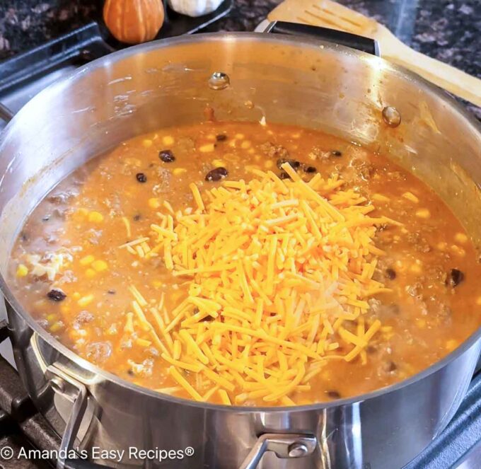 Adding shredded cheddar to the pot.